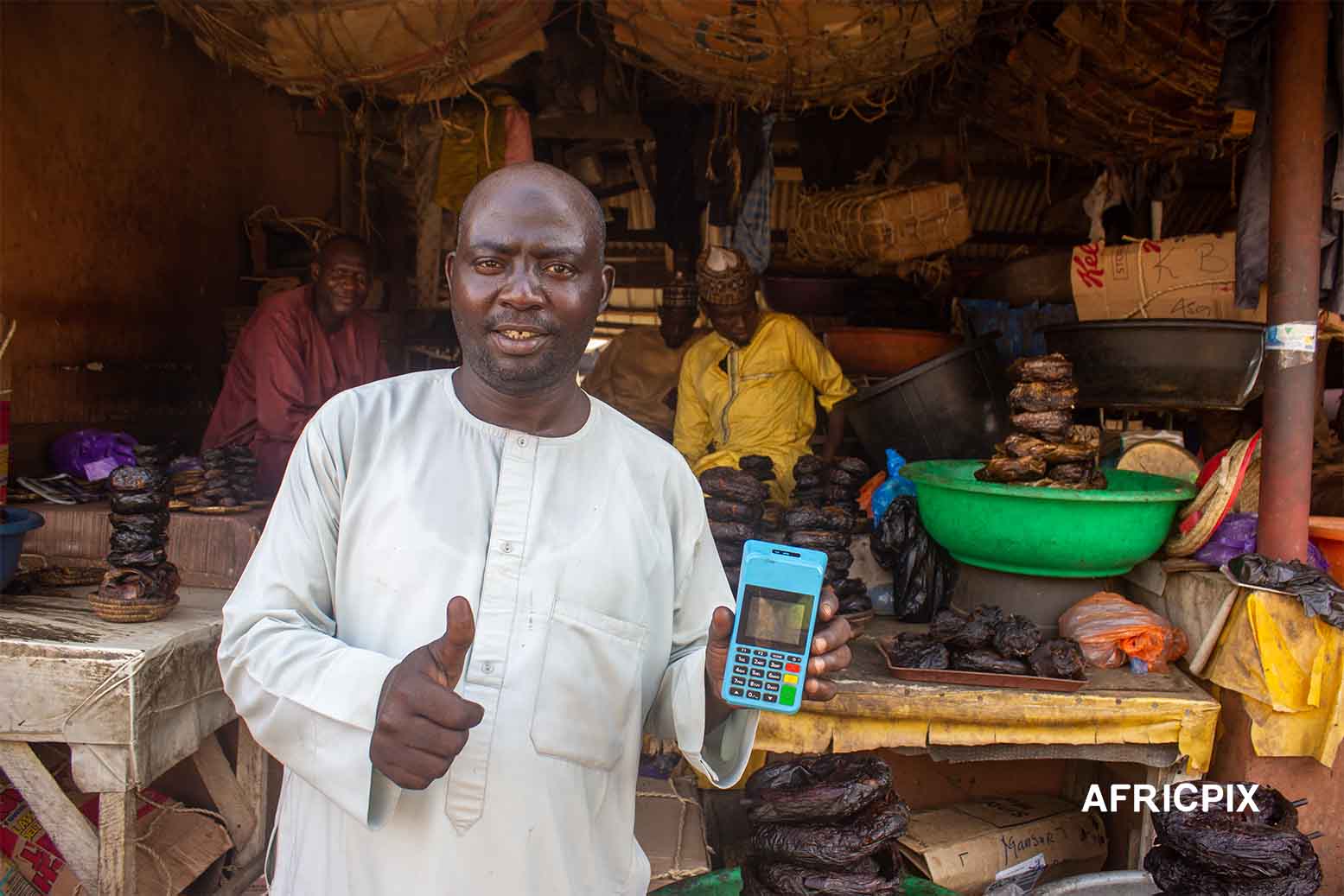 Nigeria Market Man In Front of Shop Holding POS Machine