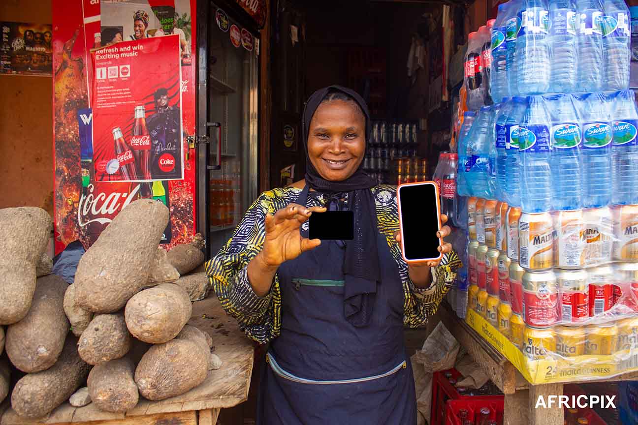 Nigeria Market Woman In Front of Shop Pointing at Credit Card and Phone