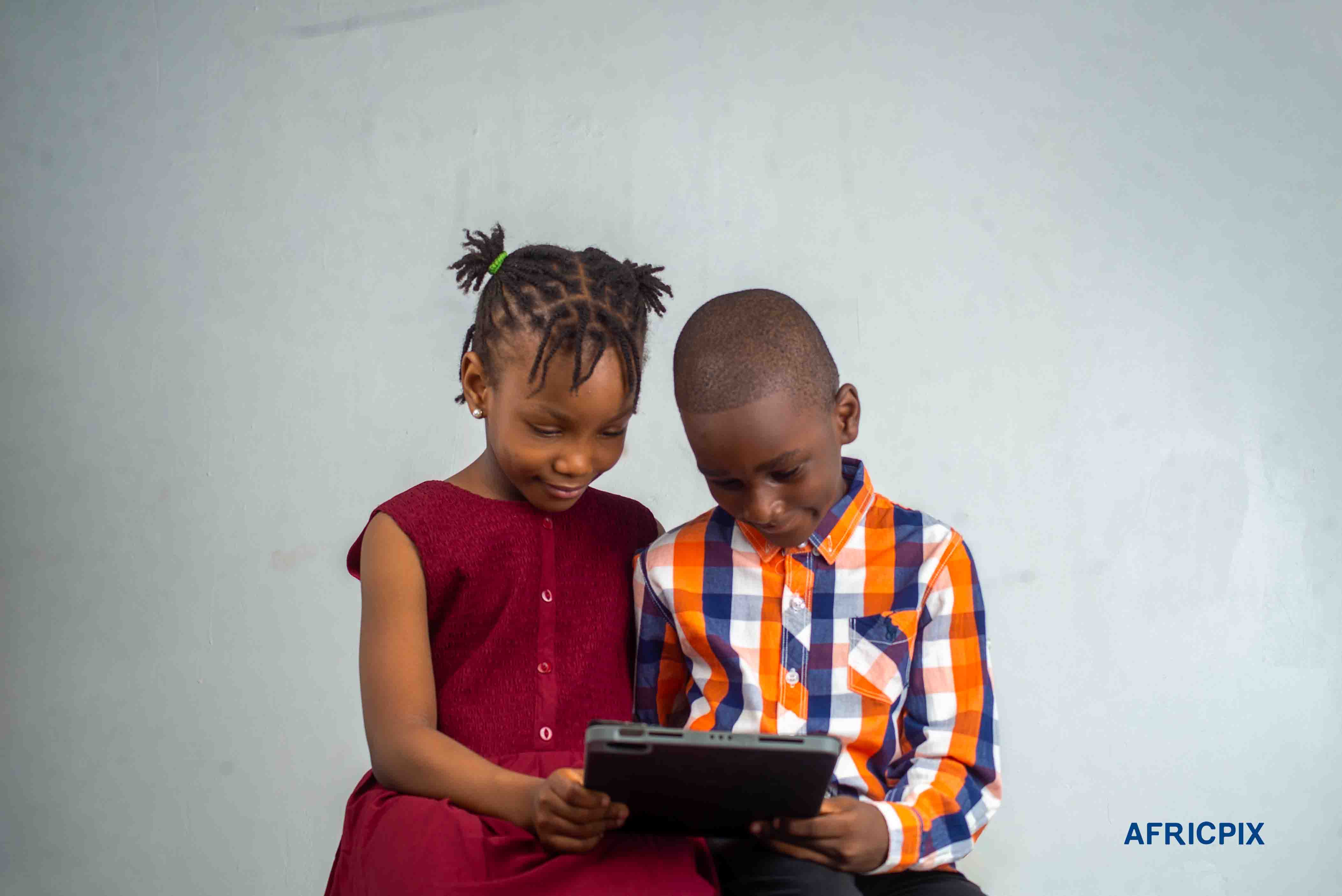 Nigeria Child Boy and Girl Sitting Smiling Looking Tablet Ipad
