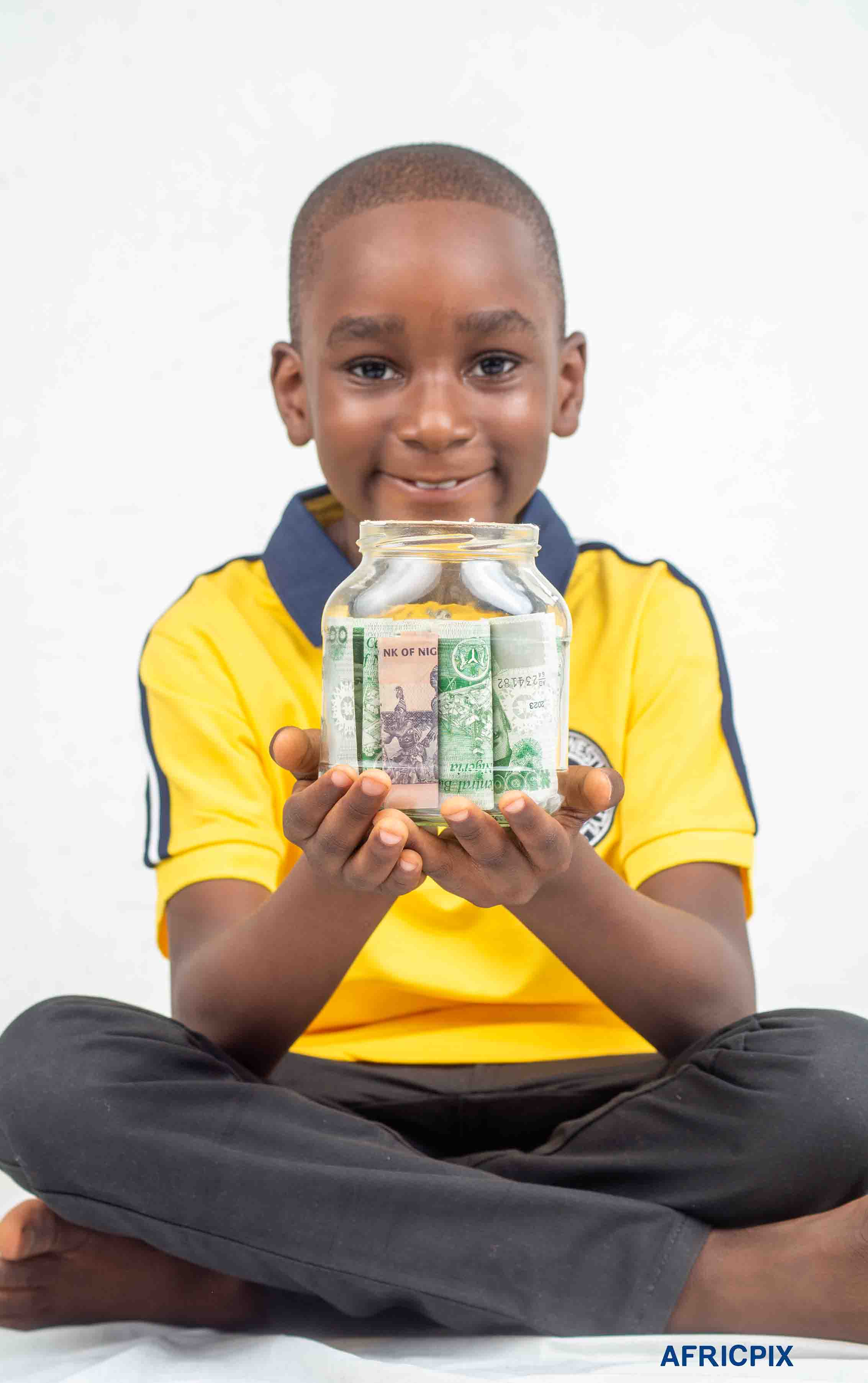 Nigeria Boy Child Sitting Down Holding Naira In Jar